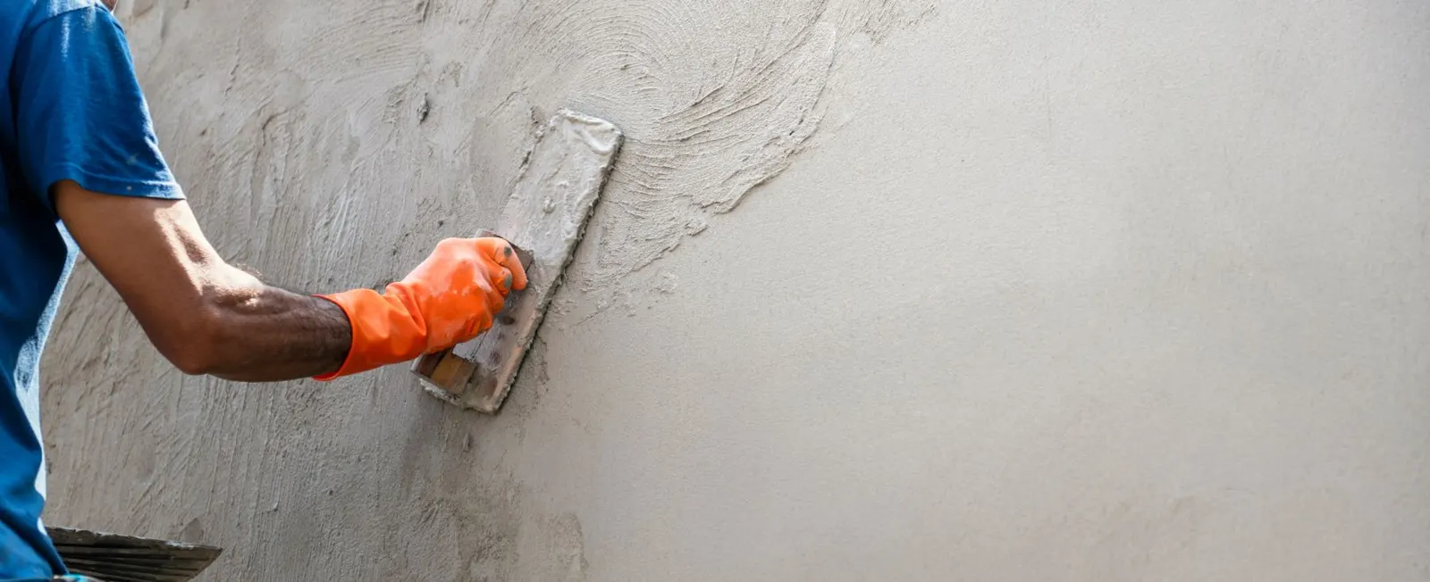 Plaster being smoothed across a wall with a float