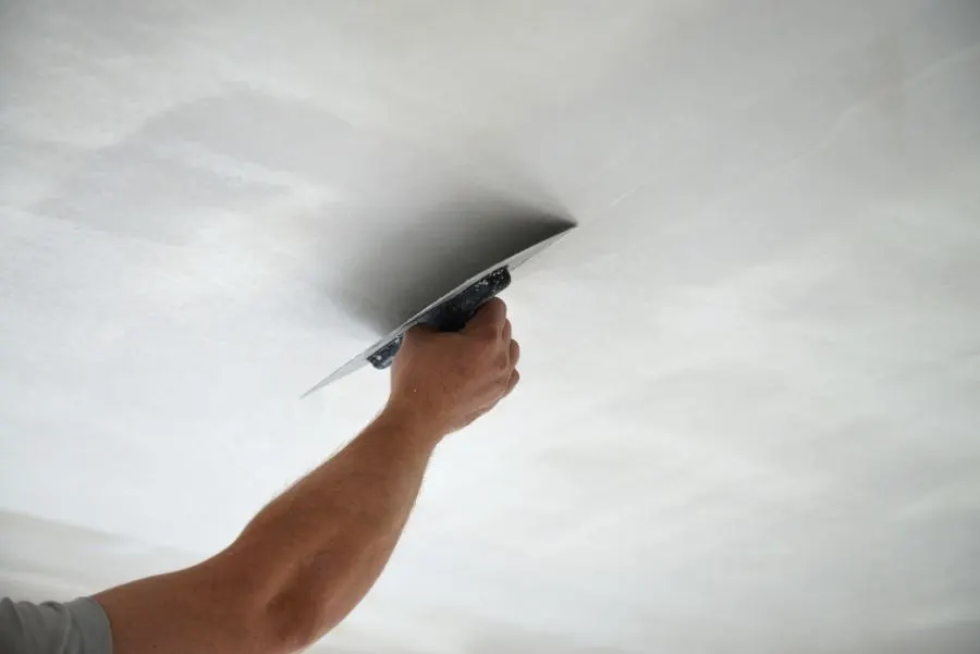 Plasterer smoothing a ceiling with a steel trowel